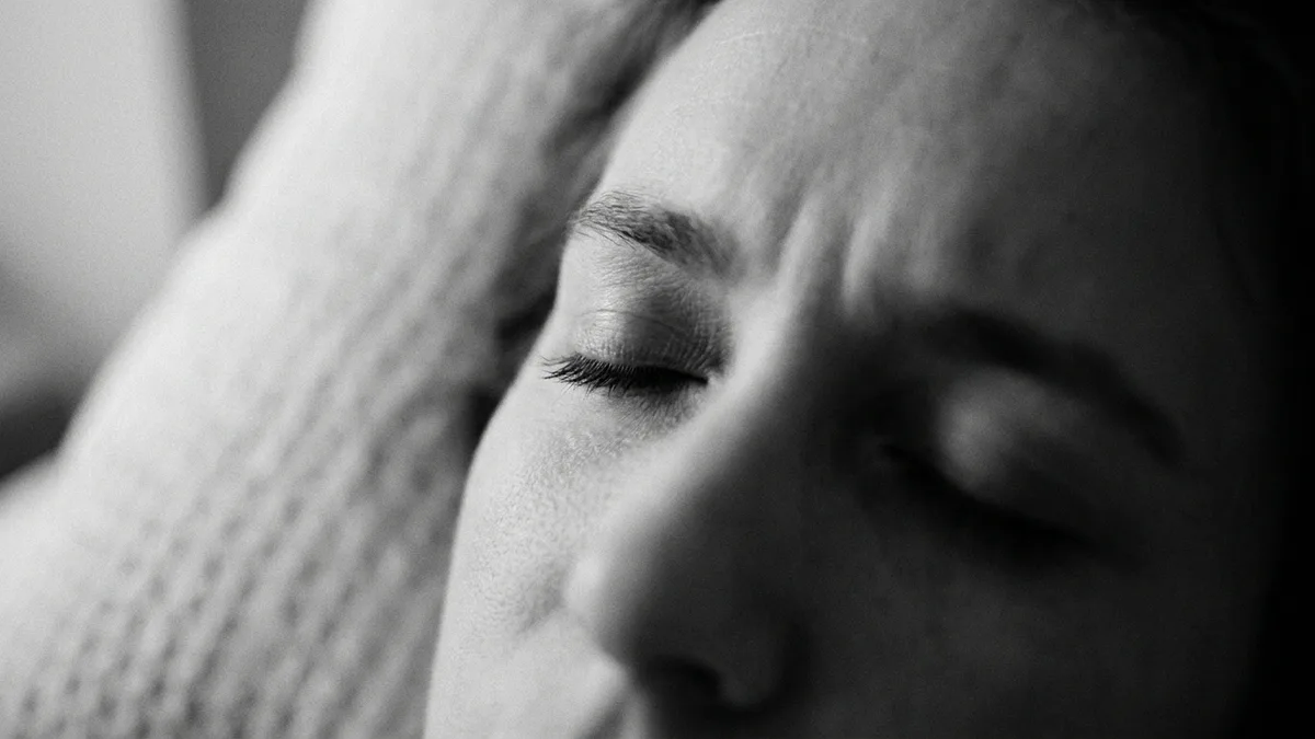 Close-up of closed human eyes in soft warm bedroom light suggesting REM dreaming